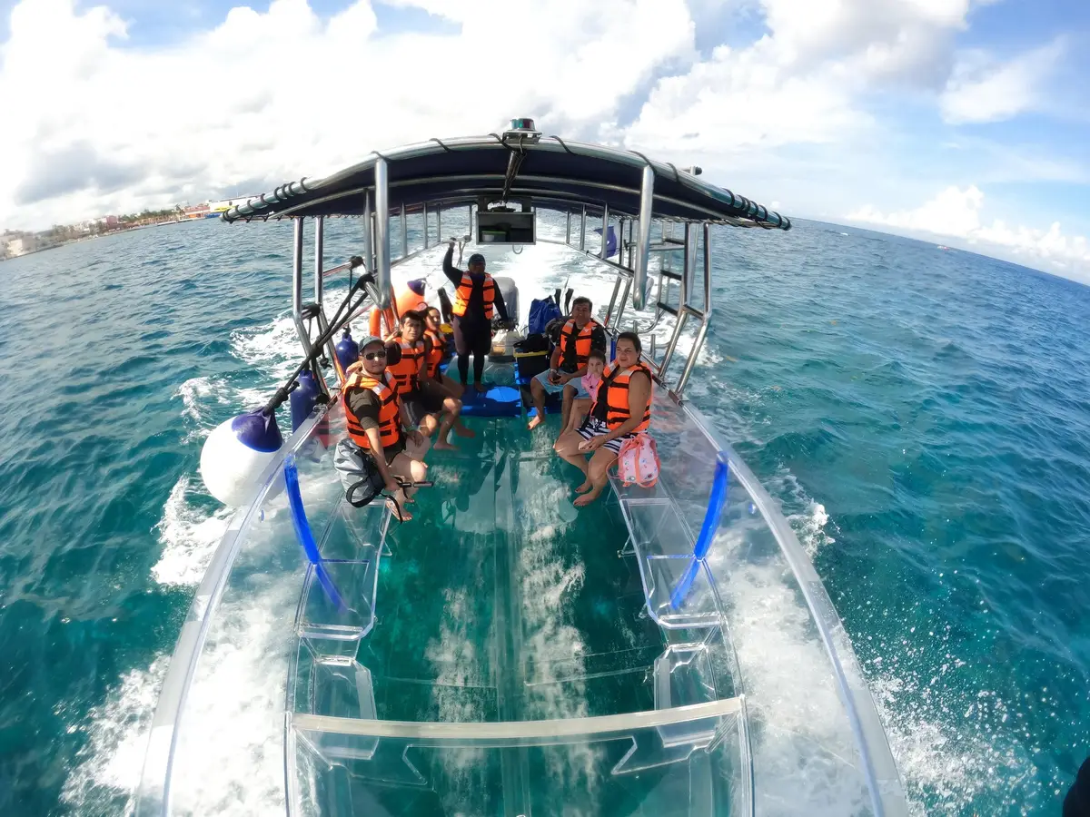 Transparent-hull boat on clear water above an artificial reef on a Cozumel boat tour from Muelle Fiscal